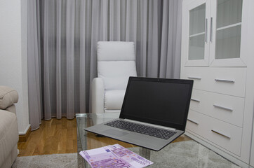500 euro bills and a computer on a table in the living room of a house