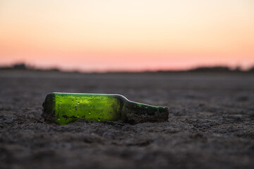 an old green bottle at the bottom of a dry pond. soil erosion. the water's gone. the bottom of the...