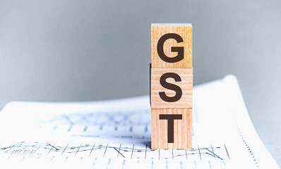 GST word written on wood block. Wooden block with words GST - acronim GST - Goods and Services Tax.