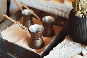 Preparation of Turkish coffee in the cezve in the sand at the cafe bar