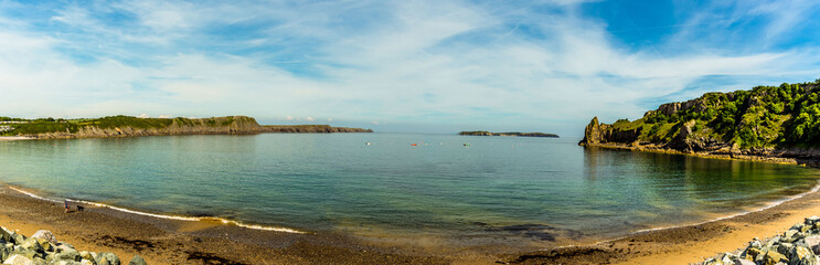 The circular bay of Lydstep Haven, Wales with Caldey Island in the distance in early summer