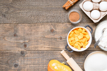 Top view raw ingredients for cooking pumpkin pie on wooden background with copy space. Bakery background.