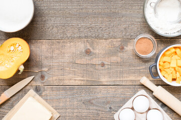 Top view raw ingredients for cooking pumpkin pie on wooden background with copy space. Bakery background.