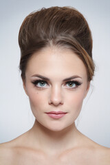 Vintage style portrait of young beautiful woman with fancy hair bun and natural makeup