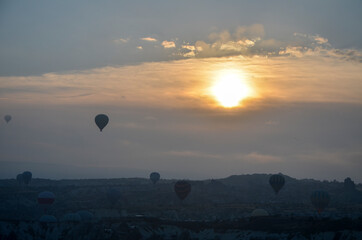 Colorful hot air balloons flying over mountains landscape and the valley at Cappadocia in the sunrise sky at foggy morning
