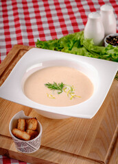 A bowl of creamy potato soup with crackers bread on white plate in italian restaurant background, top view. Vegetable cream soup. Italy food. Close up. space