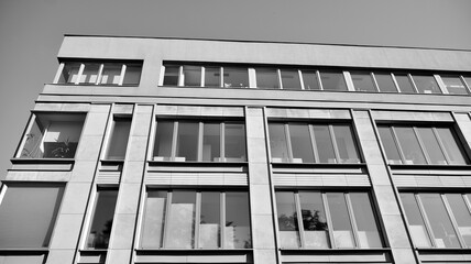 Modern office building wall made of steel and glass with blue sky. Black and white.