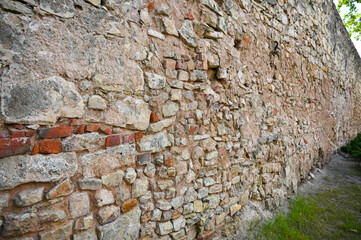 Old brick fortress wall of a small castle. Perspective view of the fence.