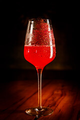 Red cocktail in a wine glass decorated with red powder.