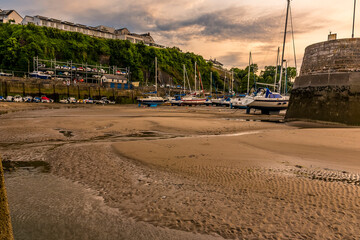 The sun is setting over Saundersfoot Harbour, Wales at low tide in  summer