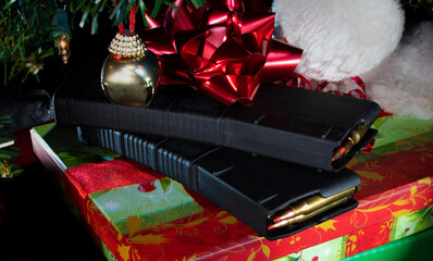 Ammo and polymer high-capacity magazines under the Christmas tree with a red bow on top - obrazy, fototapety, plakaty
