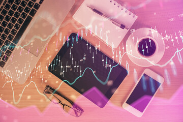 Double exposure of financial graph hologram over desktop with phone. Top view. Mobile trade platform concept.