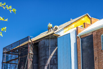 Workers Installing Roofing Materials Over Vintage Storage Tanks