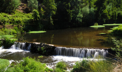 Bacia de água natural de um rio com queda de água e árvores nas margens, barragem, rio Sousa, Portugal