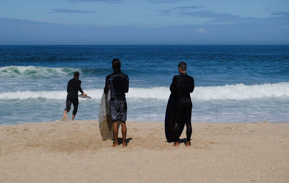Bodyboard, desporto radical, três homens na praia a praticar bodyboard, dois esperam o melhor momento para ir á água um a correr para apanhar uma onda