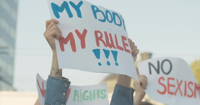 Close-up of My body my rules poster in female Caucasian hands. Unrecognizable young feminist holding banner with anti-sexism slogan on demonstration against gender discrimination. Cinema 4k ProRes HQ.