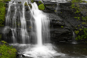 fresh water flows down dark rock to the Pacific Ocean at Alamere Falls in Point Reyes, California.