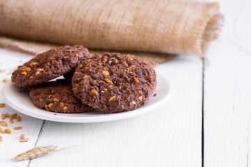 Stack of tasty cocoa cookies with wheat and peanut on rustic table, handmade or prepared snack food