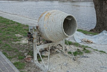 one old dirty concrete mixer stands on the street on the shore of the reservoir
