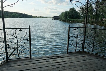 part of a gazebo with a brown iron fence with a wrought iron pattern and an open entrance against...