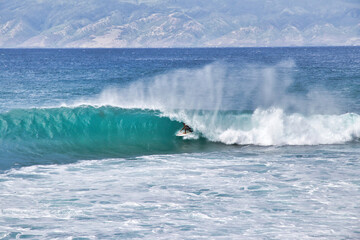 Almost completely coverd surfer in the curl of a wave.
