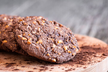 Stack of tasty cocoa cookies with wheat and peanut on rustic table, handmade or prepared snack food