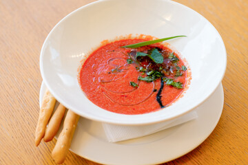 Gazpacho made from ripe tomatoes and baked pepper. Red soup with bun and herbs. Home made food. Concept for a tasty and healthy meal.
