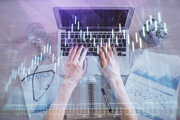 Double exposure of woman hands working on computer and forex graph hologram drawing. Top View. Financial analysis concept.