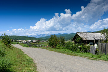 Old Russian village in Buryatia lying in the Tunkinskaya valley with mountain and clouds in summer day