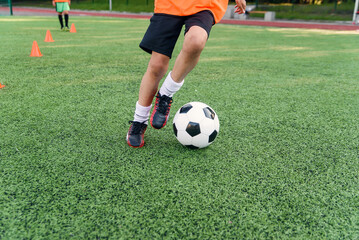 Obraz premium Soccer player kicking ball on field. Soccer players on training session. Close up footballer feet kicking ball on grass.