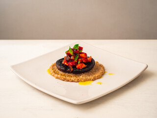 Ratatouille Stuffed Portobello Mushroom on Top of Creamy Quinotto with Olive Oil Sprinkles and Peppercorn served on Square White Plate