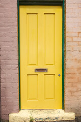 Yellow door: entrance to a brick dwelling.
