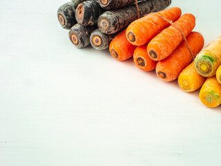 Variety of Purple, Yellow and Orange Carrots Tied Together on a White Background