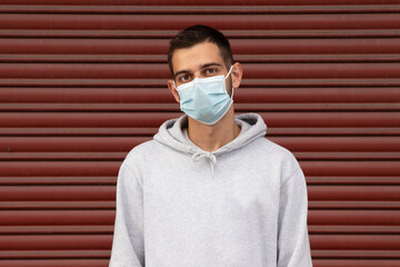 young man with mask on the street with red blind on background