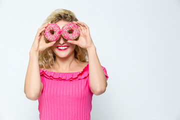 Food Ideas. Portrait of Happily Smiling Caucasian Blond Holding Pink Doughnuts in Both Hands in Front of Her Face. Posing On White.