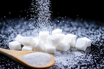 Macro Shot of White Cube Sugar And Falling Sand Sugar Along With Filled Wooden Measure Spoon. Against Black Background.