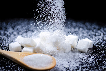 Macro Shot of White Cube Sugar And Falling Sand Sugar Along With Filled Wooden Measure Spoon....