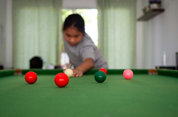 Asian woman playing snooker By aiming at his queue. Focus on the red ball.