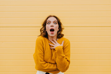 Lovely short-haired girl expressing amazement on yellow background. Photo of enthusiastic caucasian...