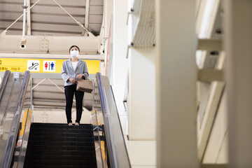 マスク姿で電車通勤をする女性