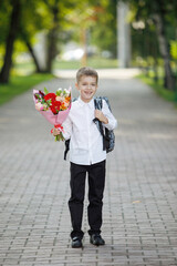 Fototapeta premium Schoolboy with flowers in a city park.