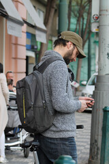 Male tourist standing on the crossroad looking at his smartphone and searching the way