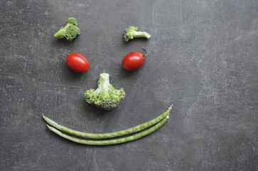 Smiling emoticon of fresh vegetables cherry tomatoes broccoli and green beans