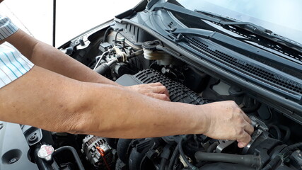 The hand of a male mechanic checking the engine.