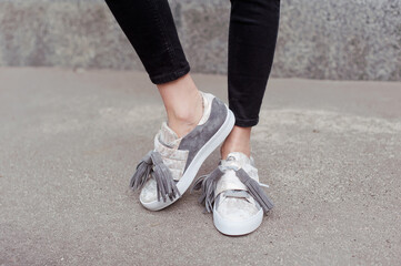 Fashionable young woman wearing black jeans and trendy gray suede sneakers. Street style. Outdoor. 