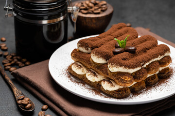 Classic tiramisu dessert and coffee grinder on ceramic plate on concrete background