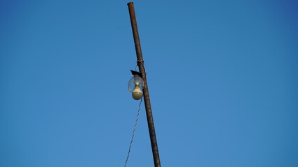 Old hanging LED Bulb on  pole with blue background. Attractive view of  modern technology.
