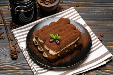 Fototapeta na wymiar Classic tiramisu dessert and coffee grinder on ceramic plate on wooden background