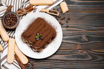 Classic tiramisu dessert on ceramic plate and savoiardi cookies on wooden background