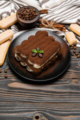 Classic tiramisu dessert on ceramic plate and savoiardi cookies on wooden background